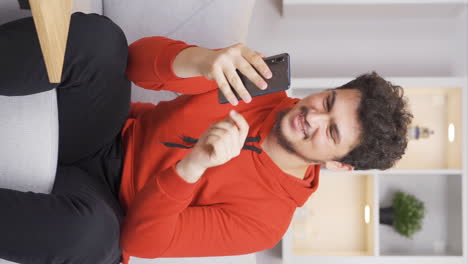 Vertical-video-of-Man-using-phone-with-happy-expression.-The-man-is-enjoying-it.
